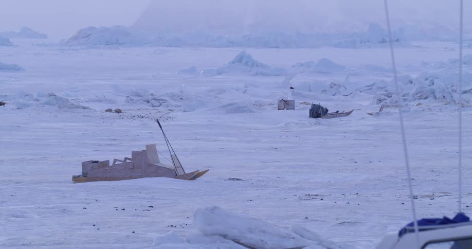Wooden boats resting on a frozen surface in a polar landscape with ice formations in the background