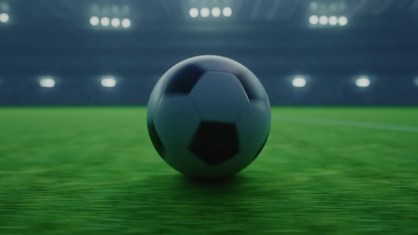 Soccer ball rolls across the field in a brightly lit stadium at night