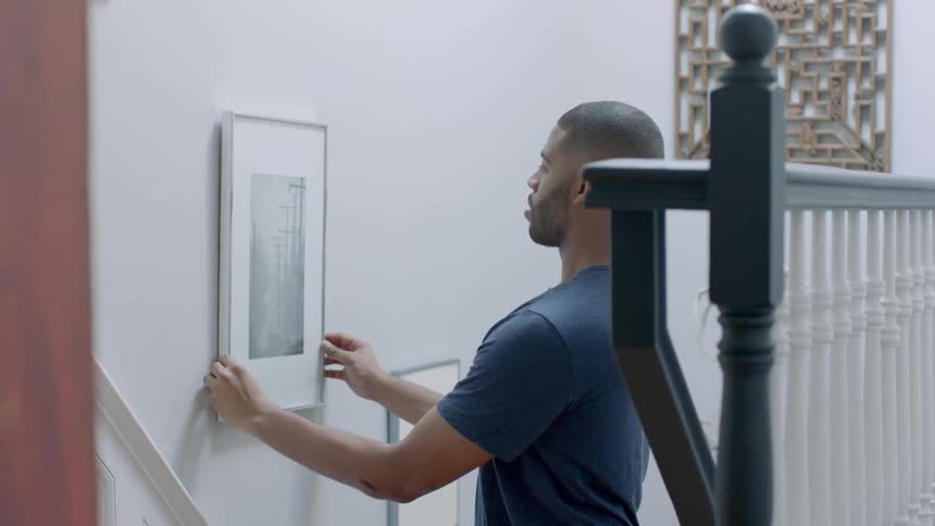Man hanging artwork up on wall