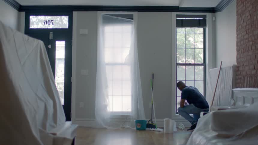 A man cleans windows in a living room