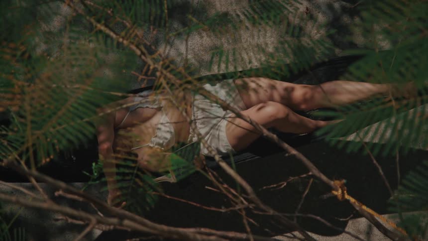 Woman sleeps outdoors in a swaying hammock on a summer day