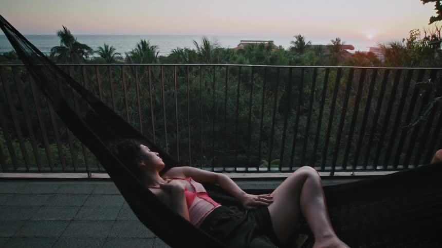 A woman taking a nap in a hammock outdoors