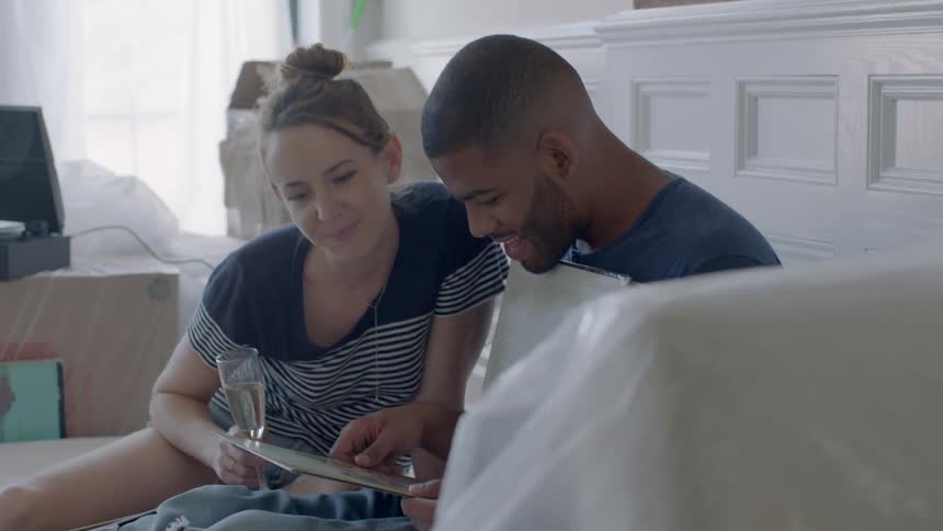 Man and woman sitting in new apartment are looking in a binder