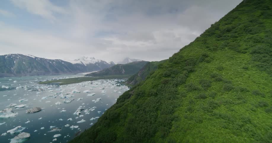 Mountains surround a body of water containing pieces of floating ice on a cloudy day