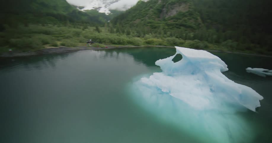 An expansive body of water scattered with ice pieces floating surrounded by mountains