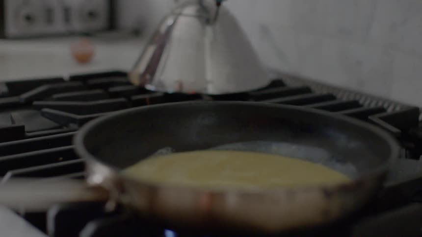 Man and woman cooking eggs in kitchen
