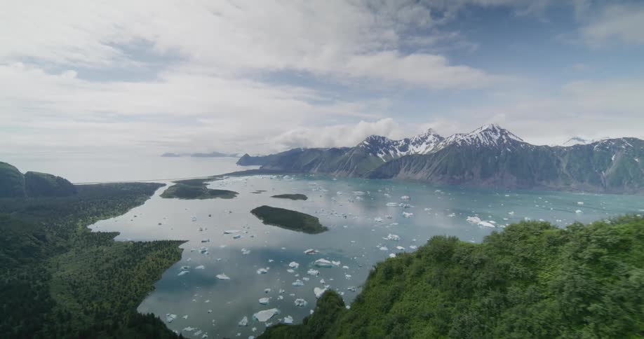 An aerial view of snow covered mountains next to a lake