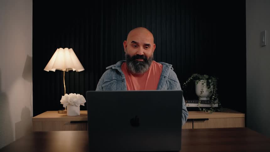 The man is talking to someone on his laptop