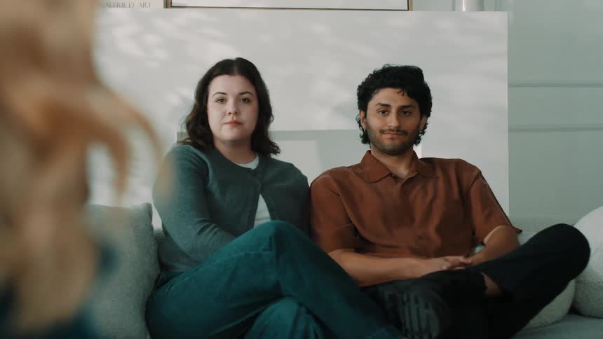 Young couple seated on a sofa during a conversation in an indoor setting