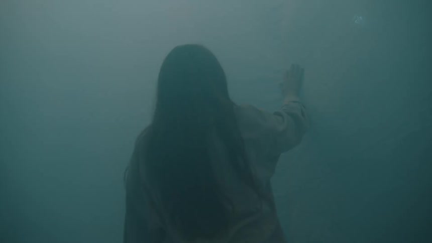 A woman reaching for a sheet in a room