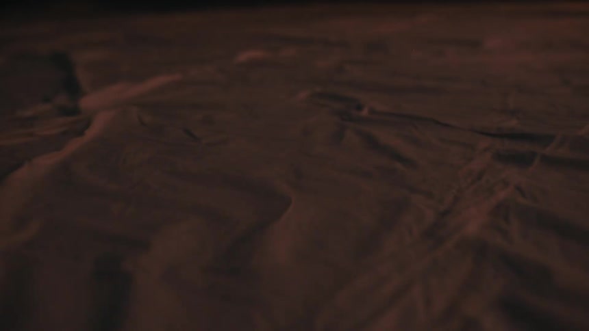 Sand with gentle ridges forming natural patterns under low lighting