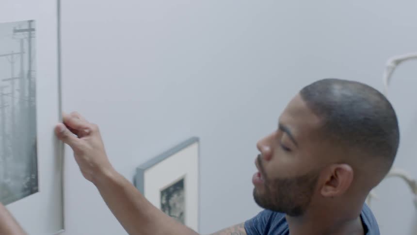 A man hangs a photograph on the wall