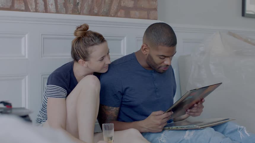 A woman and man sit against the wall talking