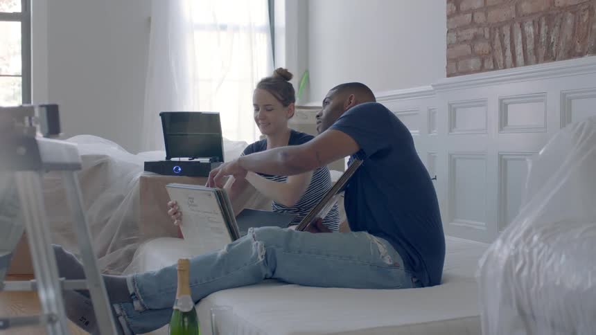 A man and woman look at records while drinking champagne