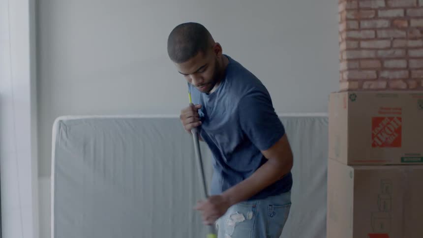 A man sweeps the floor with stacked boxes nearby