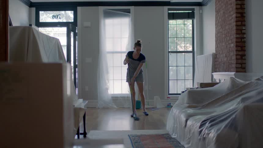 A woman sweeps the floor and uses a dust pan