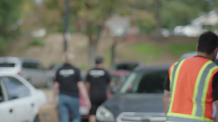 Man wearing a reflective vest talks to a driver through a car window