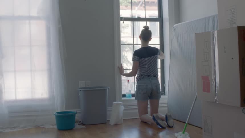 A woman wipes down an apartment window
