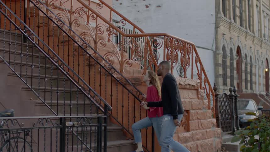 Two people hold hands walking towards a home