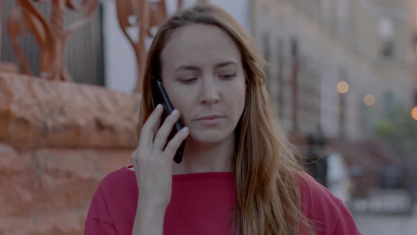 A woman stands on the sidewalk talking on the phone