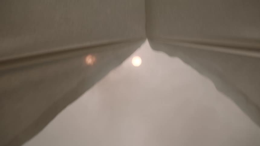 Lightcolored curtains forming a narrow angle with diffused light in the background