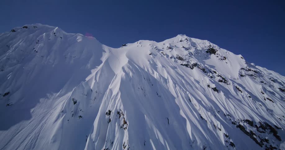 Snowcovered mountain peak with steep slopes under a clear sky