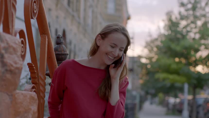 Woman talks on a phone next to a railing in a city