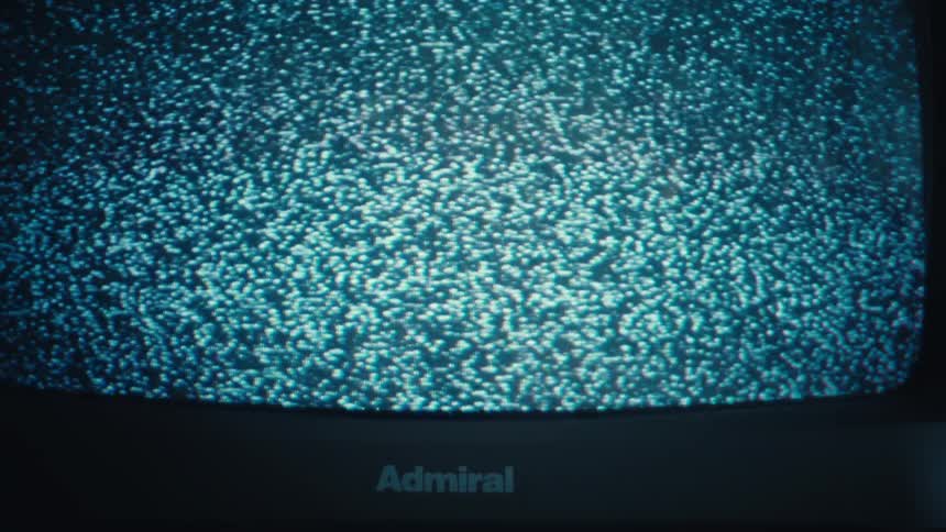A close up shot shows a television screen filled with black and white static