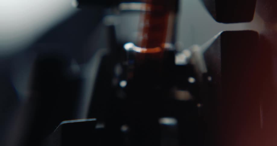 A extreme closeup shot shows a strip of ambercolored motion picture film moving quickly through the internal mechanism of a film projector