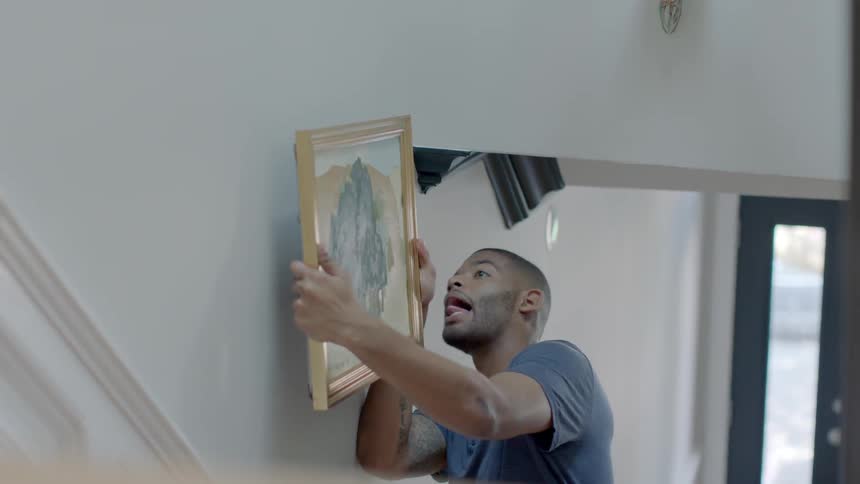 A man puts a portrait on the wall