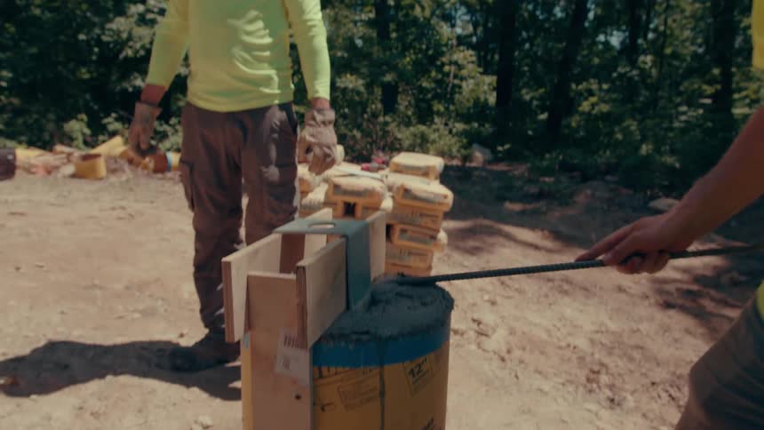 Concrete work on cylindrical structure outdoors with stacked materials in the background