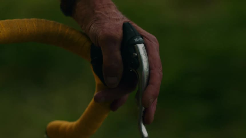 Mans hands on the handlebars as he rides his bicycle