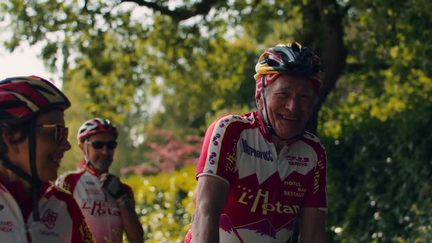 Cyclists in red and white uniforms in lush setting smiling and enjoying outdoor ride