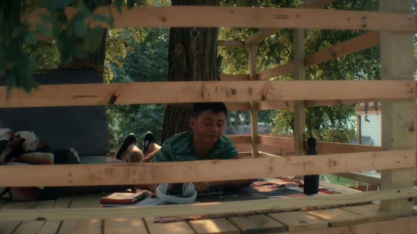 A child outdoors shutting his laptop in his treehouse finishing school