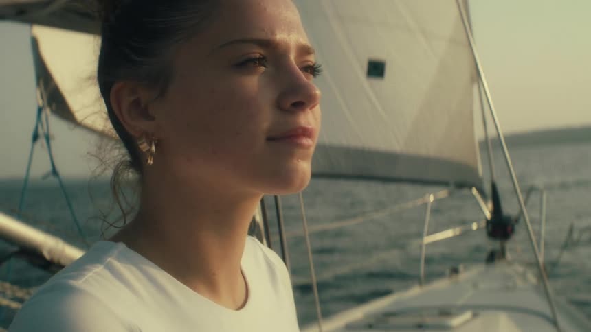 Woman gazes at horizon aboard sailboat during navigation