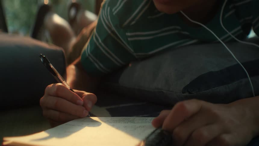 A child writing notes in a notebook doing homework outside