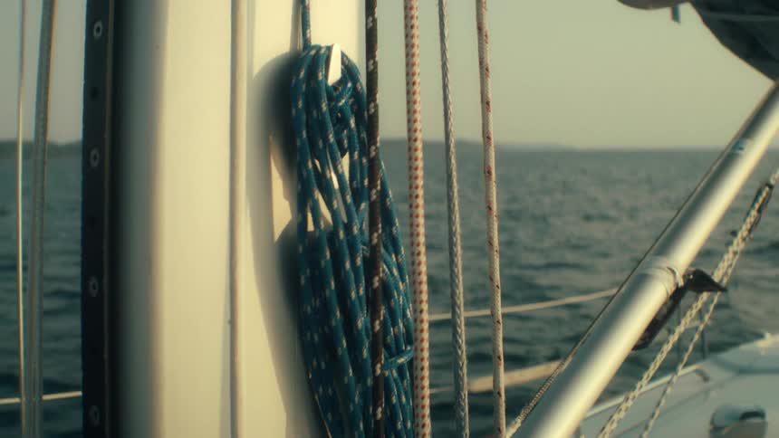 Ropes on a boat sway slightly as the watercraft moves across the water during the daytime