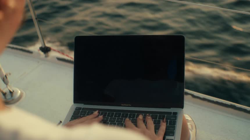 The woman is typing on her laptop while the boat is moving