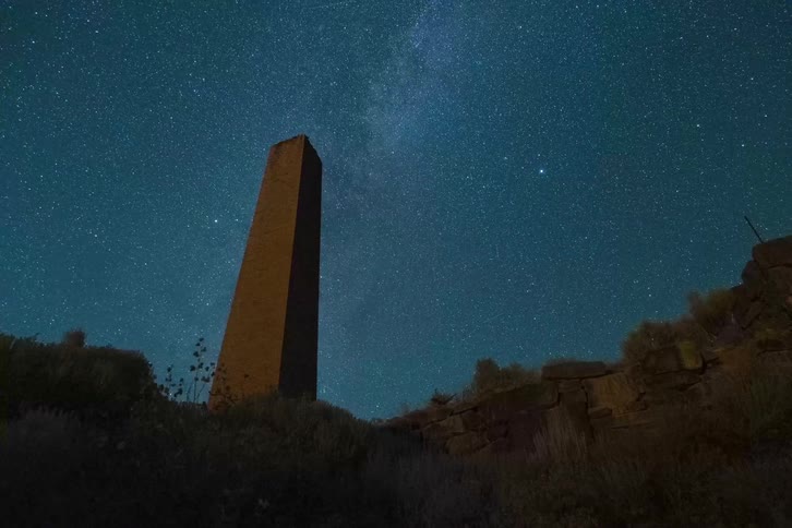 Tower standing tall as the stars of the milky way move across the night sky
