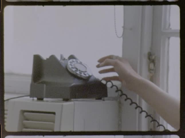 A woman entering numbers on an old rotary phone