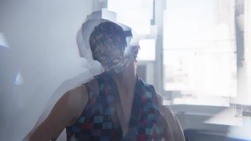 The model poses wearing a metallic mask