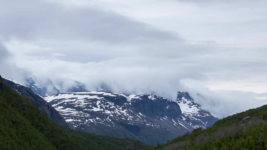Billowing clouds above a snow capped mountain
