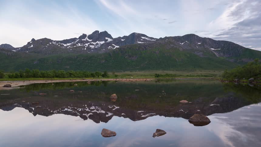Clouds float over a reflective mountain lake