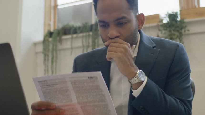 The man looks frustrated while reading paperwork