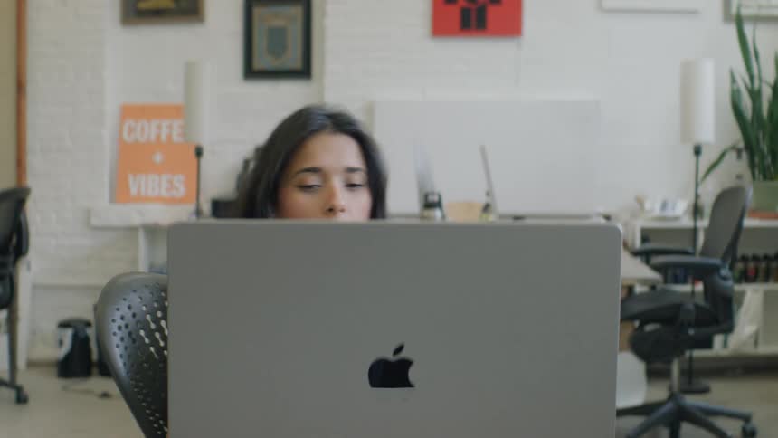Teenage girl sitting at a desk with a laptop computer leans back in her chair