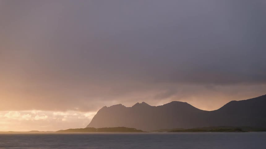 Sunset clouds flowing over ocean waters and mountains