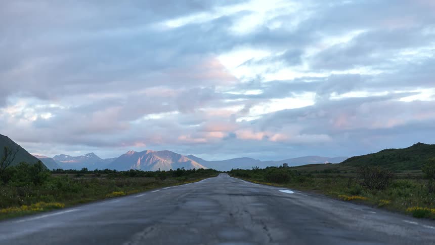 Time lapse of clouds rolling over plains and empty road