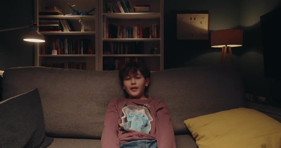 A boy enthusiastically plays a video game while holding a controller in a cozy living room