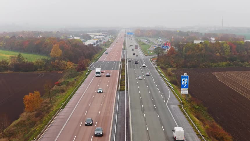 Highway with divided lanes and traffic in both directions crossing rural and wooded areas