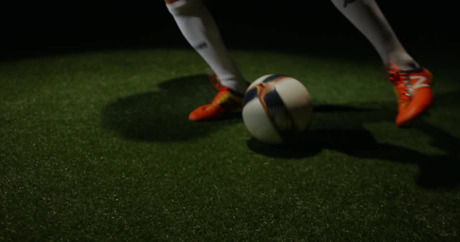A man is kicking a soccer ball on astro turf